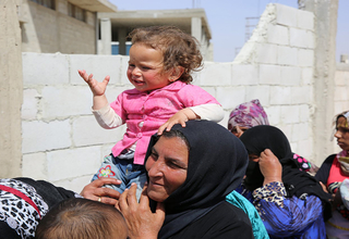 A woman holds her young daughter at a migrant camp in Syria. UNFPA Syria