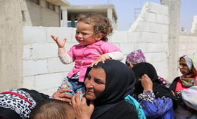A woman holds her young daughter at a migrant camp in Syria. UNFPA Syria
