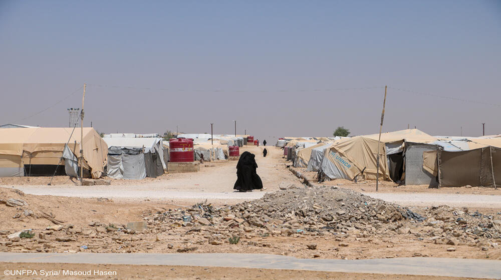 A woman walks through Al-Hol camp, where resilience meets the challenges of daily life